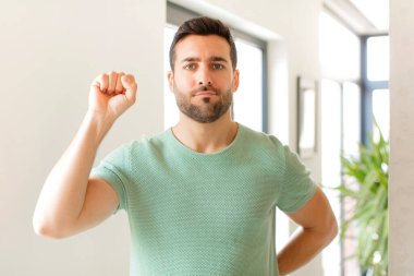 Yakışıklı adam ciddi, güçlü ve asi hissediyor, yumruğunu kaldırıyor, protesto ediyor ya da devrim için savaşıyor.