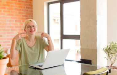 Güzel öğrenci kendine güvenerek gülümsüyor. Geniş bir gülümseme, pozitif, rahat, tatmin olmuş bir tavır sergiliyor.