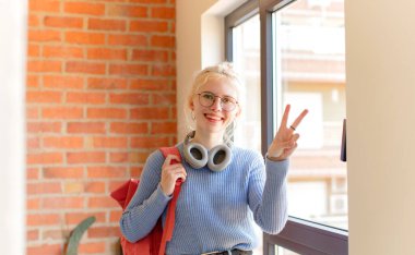 Güzel bir öğrenci gülümsüyor ve arkadaş canlısı görünüyor. İki ya da iki numarayı gösteriyor. Elleri önde, geri sayıyor.