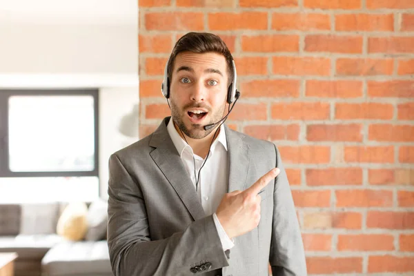 Apuesto Telemarketer Mirando Emocionado Sorprendido Apuntando Hacia Lado Hacia Arriba —  Fotos de Stock