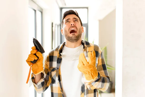 handyman looking desperate and frustrated, stressed, unhappy and annoyed, shouting and screaming