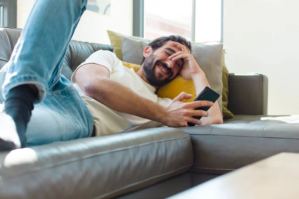 Jovem Barbudo Homem Descansando Sofá Com Seu Smartphone — Fotografia de Stock