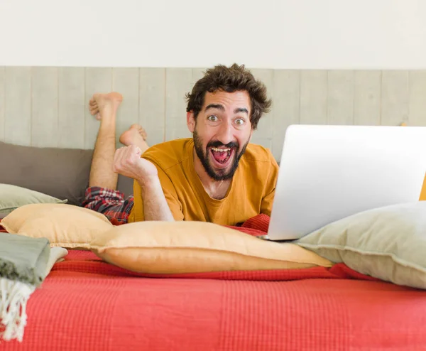 ベッドの上にノートパソコンを持った若い髭の男が — ストック写真