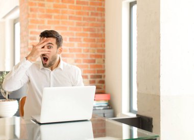 Yakışıklı iş adamı, şok olmuş, korkmuş ya da korkmuş görünüyor. Yüzü elle kaplanmış ve parmaklarının arasından gizlice bakıyor.