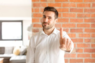 Yakışıklı işadamı gururla gülümsüyor ve bir numaralı pozunu başarıyla veriyor, kendini lider gibi hissediyor.