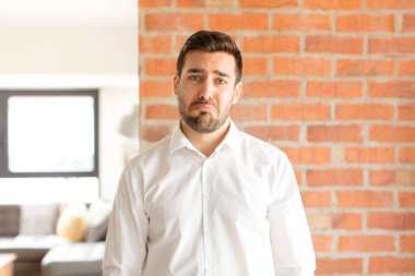 Yakışıklı iş adamı üzgün ve mızmız, mutsuz bir bakışla ağlıyor, olumsuz ve hayal kırıklığına uğramış bir tavırla ağlıyor.