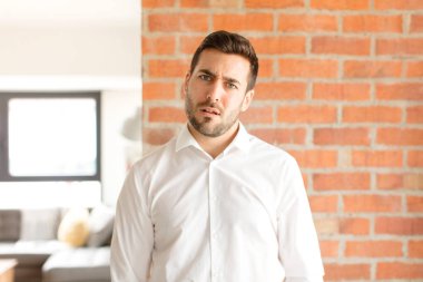 handsome businessman feeling puzzled and confused, with a dumb, stunned expression looking at something unexpected