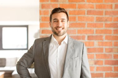 Yakışıklı işadamı mutlu bir şekilde gülümsüyor. Kendine güvenen, olumlu, gururlu ve arkadaş canlısı bir tavırla.