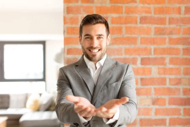 Yakışıklı iş adamı gülerek güler yüzlü, kendine güvenen, olumlu bakışlı, bir nesne ya da konsept sunan ve gösteren