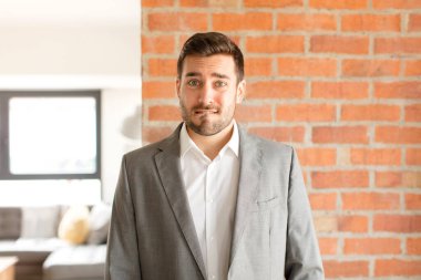 Yakışıklı işadamı şaşırmış ve kafası karışmış görünüyor. Sinirli bir hareketle dudağını ısırıyor. Sorunun cevabını bilmiyor.