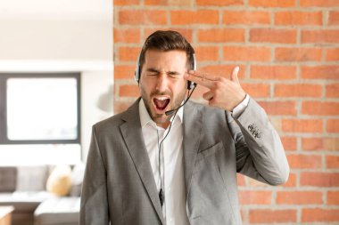 Yakışıklı pazarlamacı mutsuz ve stresli görünüyor, intihar jesti elle silah işareti yapıyor, kafasını işaret ediyor.