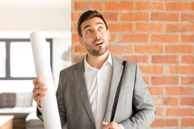 Yakışıklı mimar mutlu bir şekilde gülümsüyor ve hayal kuruyor ya da şüphe ediyor.