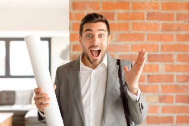 Yakışıklı mimar mutlu, heyecanlı, şaşırmış ya da şaşırmış hissediyor, gülümsüyor ve hayrete düşüyor.