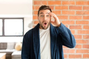 Yakışıklı adam mutlu, şaşkın ve şaşırmış görünüyor, gülümsüyor ve inanılmaz ve inanılmaz iyi haberleri fark ediyor.