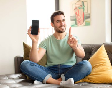 Yakışıklı adam gururla gülümsüyor ve gururla bir numaralı pozunu veriyor, kendini lider gibi hissediyor.