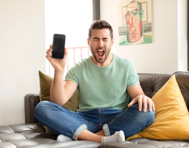 Yakışıklı adam agresif bir şekilde bağırıyor, sinirli, sinirli, öfkeli ya da sinirli görünüyor.