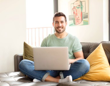 Yakışıklı adam mutlu bir şekilde gülümsüyor, eli kalçasında ve kendinden emin, olumlu, gururlu ve arkadaş canlısı.