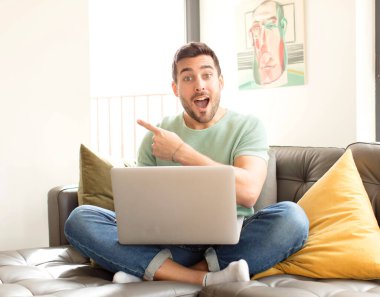 Yakışıklı adam heyecanlı ve şaşırmış görünüyor. Yana ve yukarı doğru uzayı gösteriyor.