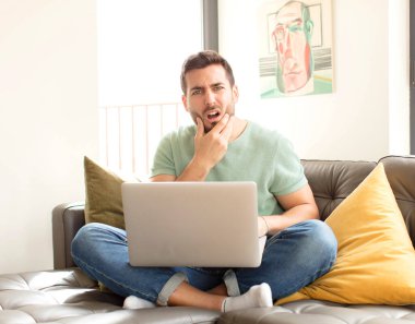 Ağzı ve gözleri açık, eli çenesinde olan yakışıklı bir adam, nahoş bir şekilde şokta, ne ya da vay canına diyor.