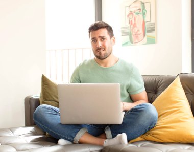 Yakışıklı adam şaşkın ve şaşkın görünüyor, gergin bir hareketle dudağını ısırıyor, sorunun cevabını bilmiyor.