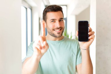 Yakışıklı adam gururla gülümsüyor ve gururla bir numaralı pozunu veriyor, kendini lider gibi hissediyor.