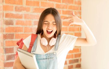 Mutsuz ve stresli görünüyor, intihar jesti elle silah işareti yapıyor, kafasını işaret ediyor.