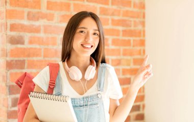 Neşeli bir şekilde gülümseyen, mutlu hisseden, kenarı ve yukarıyı gösteren, kopya uzayda nesneleri gösteren