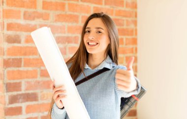 Güzel mimar gururlu, tasasız, kendinden emin ve mutlu, başparmağıyla olumlu gülümsüyor.