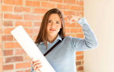 Güzel mimar, kafası karışık ve şaşkın hissediyor. Deli, deli ya da aklını kaçırmış olduğunu gösteriyor.