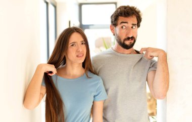 Genç çift stresli, endişeli, yorgun ve hayal kırıklığına uğramış, gömleğini çekmiş, sorunlu görünüyor.