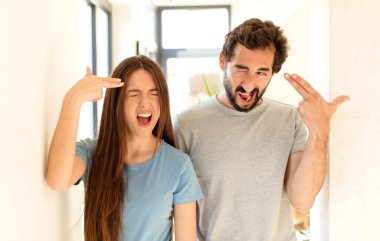 Genç çift mutsuz ve stresli görünüyor, intihar jesti elleriyle silah işareti yapıyor, kafasını işaret ediyor.