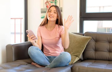 Güzel bir kadın mutlu ve neşeyle gülümsüyor, el sallıyor, seni selamlıyor ve selamlıyor, ya da hoşça kal diyor.