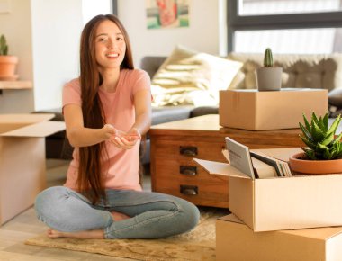 Güzel bir kadın mutlu bir şekilde gülümsüyor arkadaş canlısı, kendinden emin, pozitif bakışlı, bir nesne ya da konsept sunuyor ve gösteriyor.