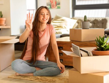 Güzel bir kadın gülümsüyor ve arkadaş canlısı görünüyor. Üç ya da üç numarayı gösteriyor. Elleri önde, geri sayıyor.