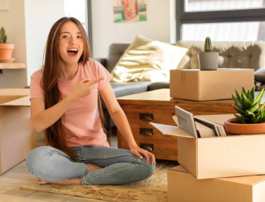 Güzel bir kadın heyecanlı ve şaşırmış görünüyor. Yana ve yukarı doğru uzayı gösteriyor.