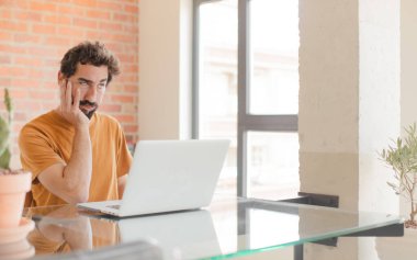 Genç sakallı adam yorgun, sıkıcı ve sıkıcı bir görevden sonra sıkılmış, hayal kırıklığına uğramış ve uykulu hissediyor.