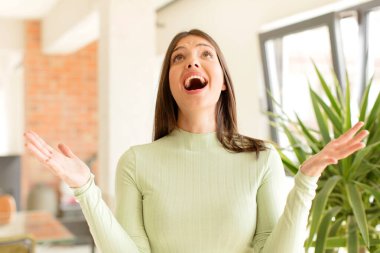 Güzel bir kadın kendini mutlu, şaşkın, şanslı ve şaşırmış hissediyor. Zaferi kutlarken iki eli havada.