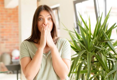 Güzel bir kadın endişeli, üzgün ve korkmuş hissediyor, elleriyle ağzını kapatıyor, endişeli ve berbat görünüyor.