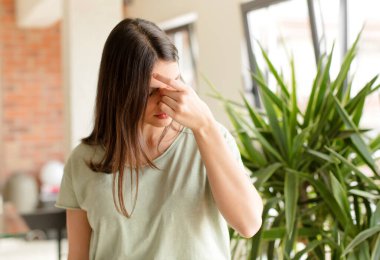 Güzel bir kadın stresli, mutsuz ve hayal kırıklığına uğramış, alnına dokunmuş ve şiddetli baş ağrısı çeken bir kadın.