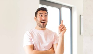 Yakışıklı adam mutlu bir şekilde gülümsüyor ve yan bakıyor, merak ediyor, düşünüyor ya da bir fikri var.