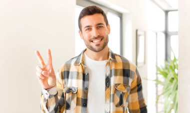 Yakışıklı adam gülümsüyor ve arkadaş canlısı görünüyor. İki ya da iki numarayı gösteriyor. Elleri önde, geriye doğru sayıyor.