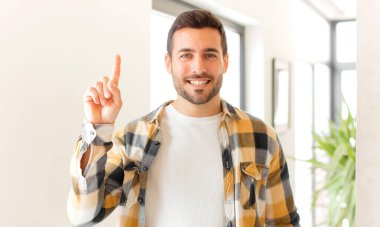 Yakışıklı adam neşeyle ve mutlulukla gülümsüyor, tek eliyle uzayı işaret ediyor.