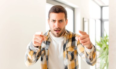 Yakışıklı bir adam kamerayı iki parmağıyla ve kızgın bir ifadeyle sana görevini yapmanı söylüyor.