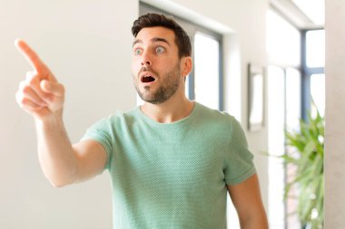 Yakışıklı adam şaşkın ve şaşırmış hissediyor, şaşırmış ve hayranlıkla yukarı bakıyor, şaşkın, açık ağızlı bir bakışla