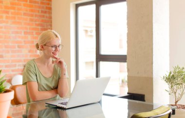 Güzel bir öğrenci mutlu ve kendinden emin bir ifadeyle gülümsüyor, elleri çenesinde, merak ediyor ve yan tarafa bakıyor.