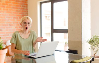 Güzel bir öğrenci şaşırmış ve şok olmuş görünüyor, çenesi düşmüş, bir objeyi elinde açık bir elle tutuyor.