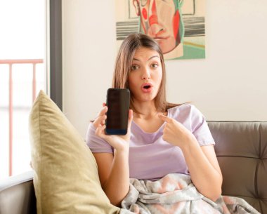 Şok olmuş ve ağzı açık, kendini işaret eden güzel bir kadın.