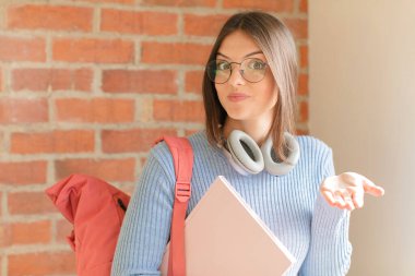 Güzel öğrenci şaşkın ve şaşkın hissediyor, şüpheci, farklı seçenekleri tartıyor ya da komik ifadeyle seçiyor.