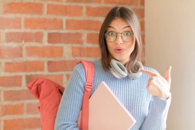 Güzel öğrenci mutlu, şaşkın ve gururlu, heyecanlı ve şaşkın bakışlarla kendini işaret ediyor.