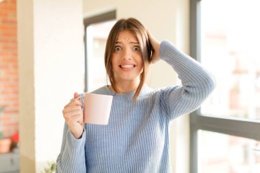 Güzel bir kadın kendini stresli, endişeli, endişeli ya da korkmuş hisseder. Elleri başının üstünde, hatayla panikler.